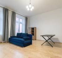 Nappali kék kanapéval és fa dekorációjú padlóval egy háromszobás lakásban.