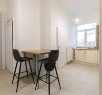 Konyha egy háromszobás lakásban bárpulttal, két székkel és nagy ablakkal.