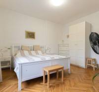 Hálószoba egy kétszobás lakásban fehér bútorokkal és fa dekorációs padlóval.