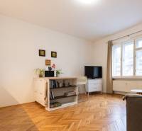 Nappali egy kétszobás lakásban világos bútorokkal és fa dekorációjú padlóval.