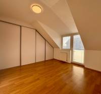 Tetőtéri szoba egy kétszobás lakásban, fa dekorációjú padlóval és beépített szekrénnyel.