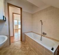 Fürdőszoba csempével a 2 szobás lakás mellett, fürdőkád és mosdó, tágas elrendezés.