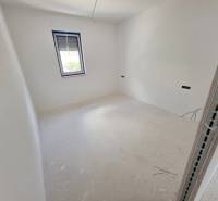 Világos szoba fehér falakkal és HR-reality márkájú ablakkal a Rekreációs apartmanban.