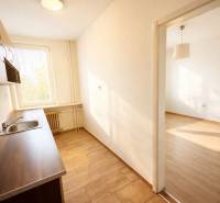 Konyha egy egyszobás lakásban fa dekor padlóval és ablakból jövő fénnyel.