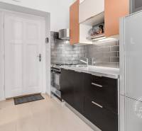 Konyha egy kétszobás lakásban fekete szekrényekkel és szürke csempékkel.