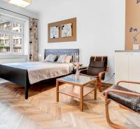 Hálószoba egy kétszobás lakásban ággyal, székekkel és fa dekor padlóval.