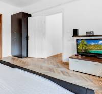 Hálószoba egy kétszobás lakásban fa dekor padlóval, szekrényekkel és televízióval.