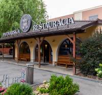 Étterem kerttel a lakótelepi épületek mellett, zöld környezet, fekete tető.