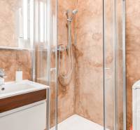 Fürdőszoba zuhanyzóval és tükörrel egy kétszobás lakásban, textúrázott felületű falakkal.