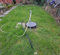 A hétvégi ház kertje Semsén, gyep kúttal és tömlővel.