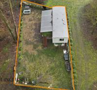 A gabčíkovi ház melletti kert, amelyet narancssárga vonal határol, fákkal körülvéve.