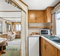 A faház belsejében konyha háztartási gépekkel és nappali virágos függönyökkel.