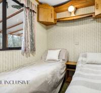 Két ágy dekorációkkal és fa szekrényekkel a kunyhó belső terében.