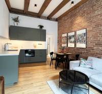 A Vajnorská utcai 2 szobás lakásban téglafal és modern gerendák találhatók, a belső tér otthonos.