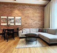 Nappali téglafallal, kanapéval, asztallal és képekkel; világos tér a Vajnorská utcán, Pozsony.