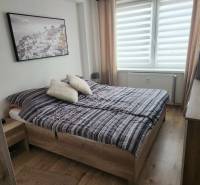 Hálószoba egy kétszobás lakásban, fa dekoros padlóval, franciaággyal és dekorációval.