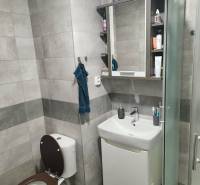 Fürdőszoba egy kétszobás lakásban modern burkolatokkal és zuhanyzóval.