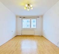 Szoba fa mintás padlóval és ablakkal egy háromszobás lakásban.