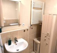 Fürdőszoba mosdóval, tükörrel és szekrénnyel egy kétszobás lakásban.