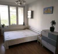 Hálószoba egy kétszobás lakásban ággyal, komóddal és fa dekorációjú padlóval.