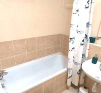 Fürdőszoba egy kétszobás lakásban káddal, mosdóval és fürdőszobai csempékkel.