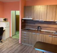 Garzonlakás konyhapulttal, asztallal, székkel és fa dekorációjú padlóval.