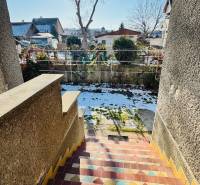 Színes lépcsők vezetnek egy családi házból Nagybélben, Partizánske, a havas kertbe.