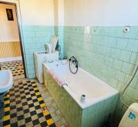 Családi ház fürdőszobája káddal, mosdóval és világoszöld csempékkel.