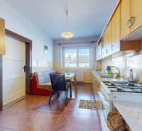 Konyha fa hatású padlóval, világos bútorokkal és étkezőasztallal egy családi házban.