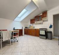 Világos konyha családi házban fa szekrényekkel és tetőablakkal.