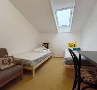 Szoba egy családi házban tetőablakkal, két ággyal és egy székkel.