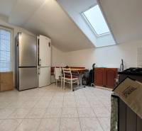 Családi ház konyhája ferde mennyezettel, nagy hűtőszekrénnyel és étkezőasztallal.