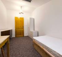 Szoba családi házban ággyal, szekrénnyel és asztallal, fehér világítással és szőnyegpadlóval kiegészítve.