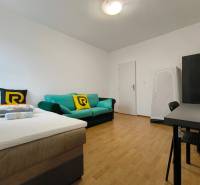 Egy családi ház szobája ággyal, kanapéval és íróasztallal, fa dekorációjú padlóval.