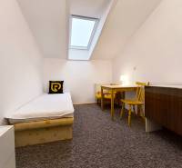 Egyszerű szoba egyszemélyes ággyal, asztallal és székekkel egy családi házban.