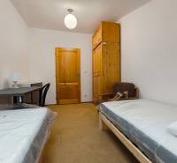 Szoba családi házban ágyakkal, asztallal, szekrénnyel és székkel.