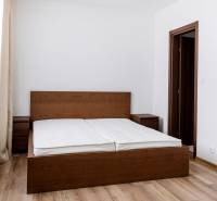 Hálószoba egy háromszobás lakásban sötét fa ággyal és fa dekorációjú padlóval.