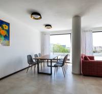 Ebédlő egy háromszobás lakásban napraforgós képpel, fa mintázatú padlóval, kilátással a teraszra.