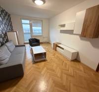 Nappali egy háromszobás lakásban szürke ülőgarnitúrával és virágos tapétával a falon.