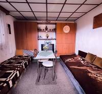 A kunyhó belseje ágyakkal, asztallal, szekrényekkel és dekorációkkal.