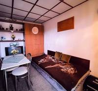 A ház belső tere kanapéval, étkezőasztallal és beépített szekrénnyel, természetes színpalettával dominál.