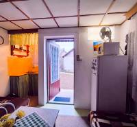 A kunyhó belseje konyhával, kanapéval és a kertbe nyíló ajtókkal.