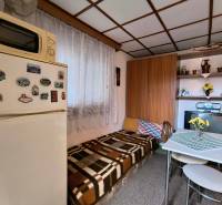 Egy kis konyha a faházban, fa dekorációval, étkezőasztallal és hűtőszekrénnyel.