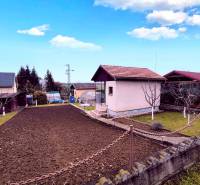 Partizánskei ház külső része rendezett kerttel, gyepesített területtel és virágágyással.