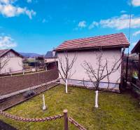 Kert házzal Partizánske városában, gyümölcsfák és megművelt föld, tiszta égbolt.