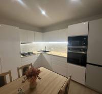 Modern konyha egy háromszobás lakásban fehér szekrényekkel és márvány burkolattal.