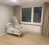 Gyerekágy egy háromszobás lakásban, fa dekoros padlóval és szürke függönyökkel.