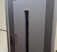 Szürke ajtó üvegkémlelővel és liftgombbal, fotó egy egyszobás lakásban.