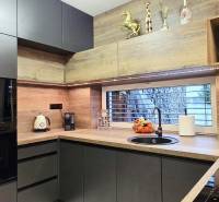 Konyha egy családi házban sötét szekrényekkel és fa dekoros padlóval.