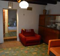 Nappali egy családi házban, piros fotellel és edényes szekrénnyel.